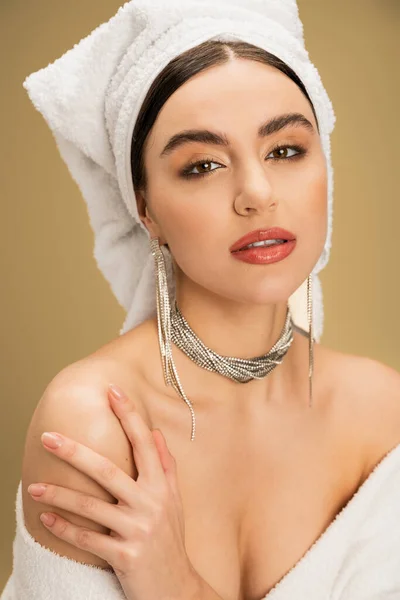 Elegant young woman with makeup and towel on head looking at camera on beige background — Stock Photo