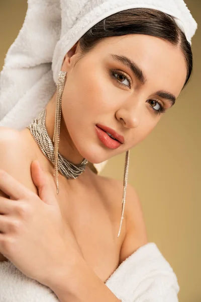 Femme sensuelle avec maquillage et serviette sur la tête en regardant la caméra sur fond beige — Photo de stock