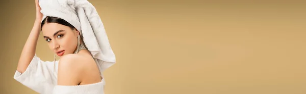 Brunette woman with makeup touching white towel on head on beige background, banner — Stock Photo