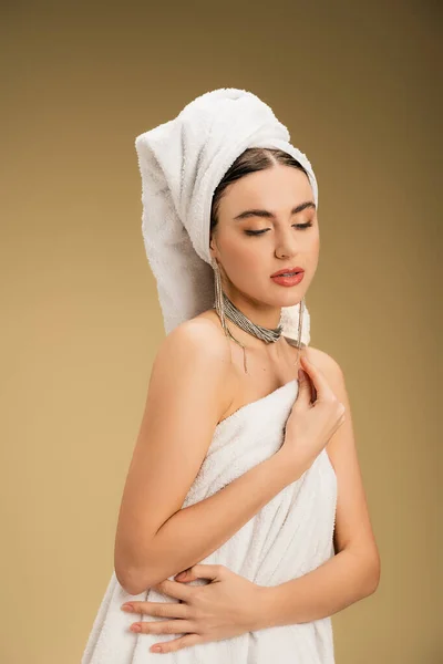 Pretty woman in jewelry holding white towel on beige background — Stock Photo