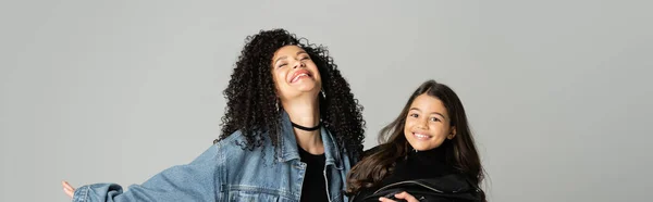Curly mother hugging happy daughter isolated on grey, banner — Stock Photo