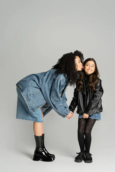 Stylish mother kissing cheerful kid on grey background — Foto stock