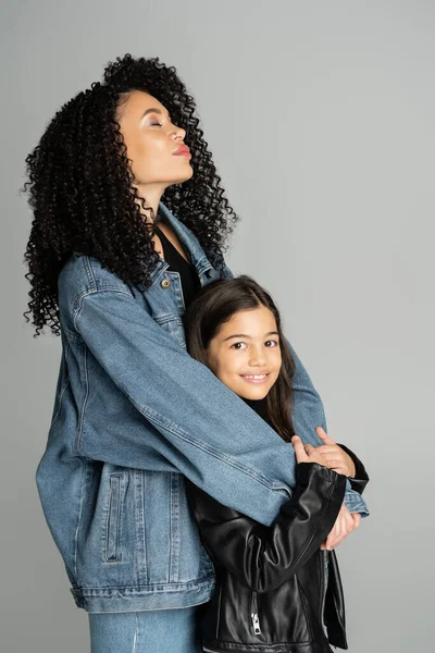 Trendy woman hugging positive preteen kid isolated on grey — Stock Photo