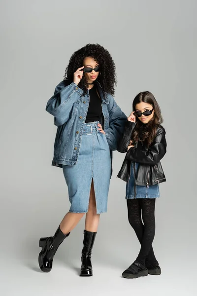 Full length of stylish mother and child posing in sunglasses on grey background — Stock Photo