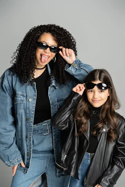 Fashionable parent and daughter posing with sunglasses isolated on grey - foto de stock