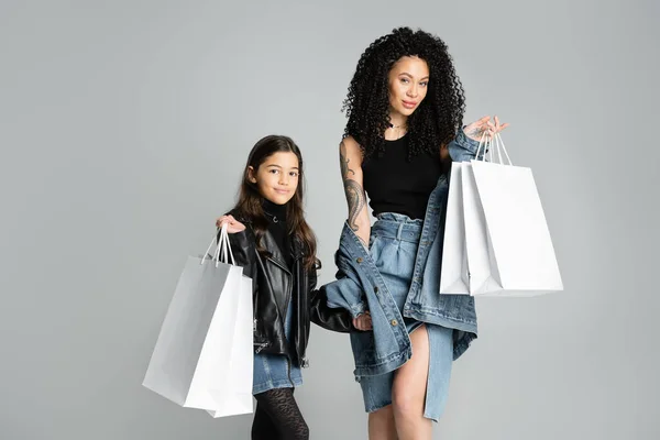 Fashionable mother and child holding purchases on grey background — Photo de stock