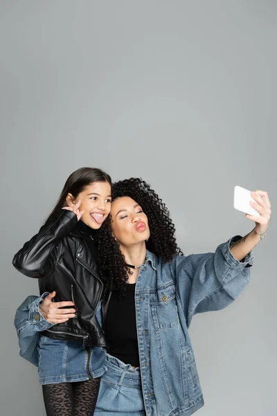 Elegante bambino e mamma sghignazzando e scattando selfie isolati su grigio — Foto stock