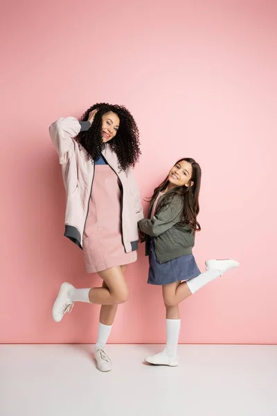 Longitud completa de la madre y la hija de moda posando sobre fondo rosa - foto de stock