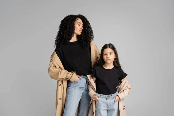 Fashionable parent and kid in trench coats posing isolated on grey — Foto stock