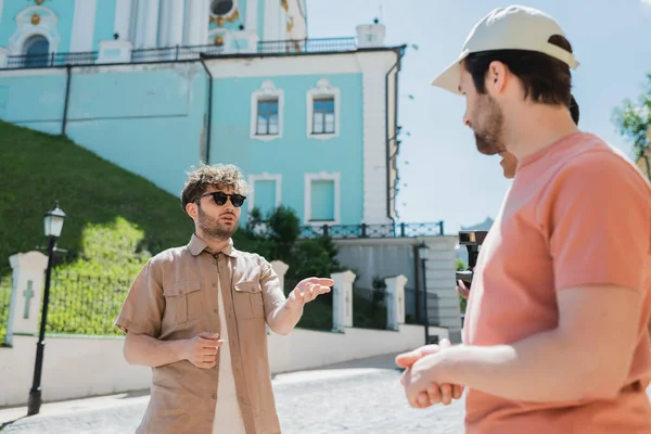 Юний екскурсовод у сонцезахисних окулярах розмовляє з багатонаціональними туристами про походження Ендрюса в Києві. — стокове фото
