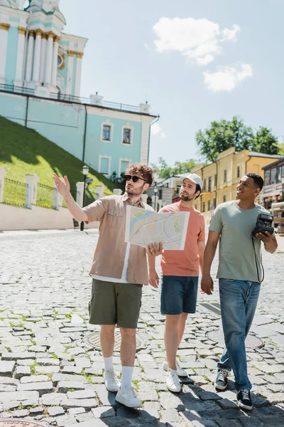Повна довжина багатонаціональних туристів, що ходять з екскурсоводом, тримаючи карту подорожей і вказуючи вручну на спуск Ендрюса в Києві. — стокове фото
