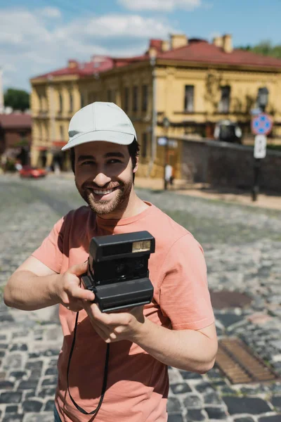 Веселий бородатий мандрівник у сонцезахисному капелюсі з вінтажною камерою на спуску Ендрюса у Києві. — стокове фото
