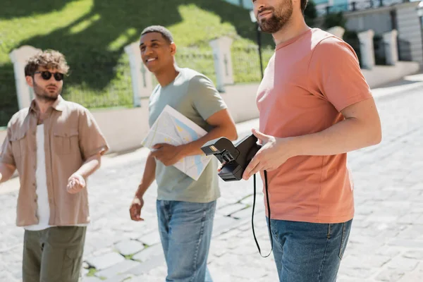 Multicultural travelers with vintage camera and city map walking with tour guide on Andrews descent in Kyiv — Stock Photo