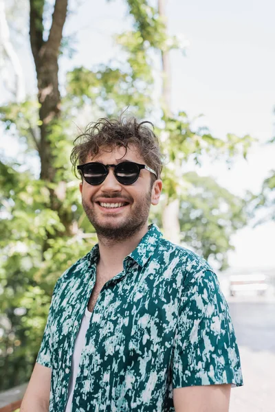 Homem alegre em óculos de sol e camisa de pé no parque de verão — Fotografia de Stock