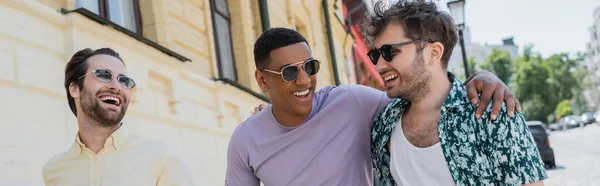 Positive interracial men in sunglasses walking on Andrews descent in Kyiv, banner — Stock Photo