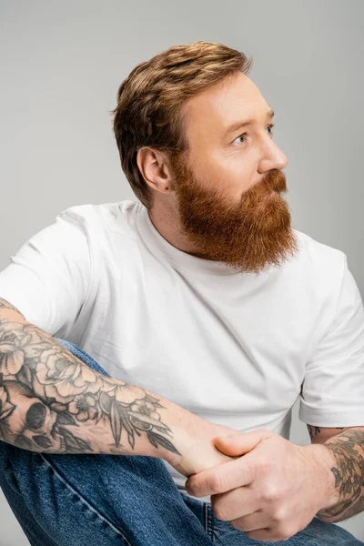 Bearded man in t-shirt and jeans looking away isolated on grey — Stock Photo