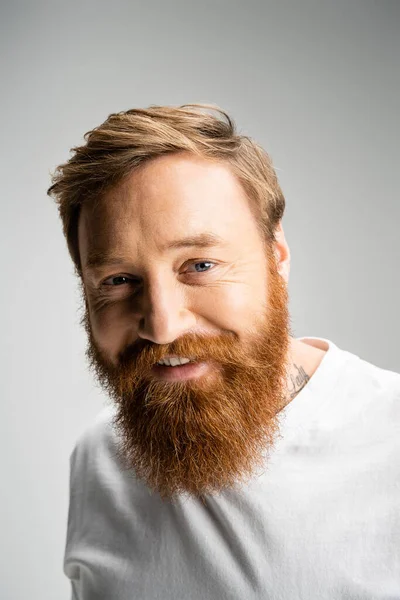 Портрет позитивного бородатого чоловіка, який дивиться на камеру ізольовано на сірому — стокове фото