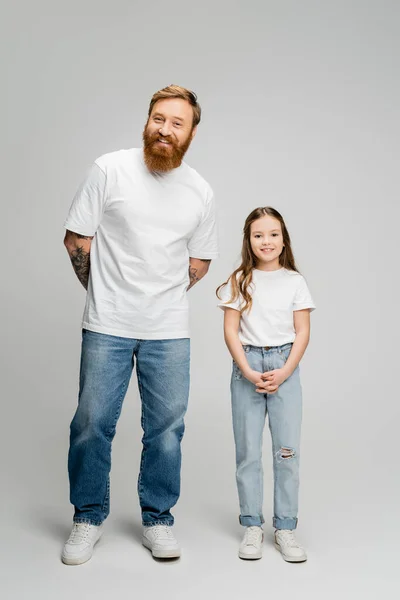 Full length of smiling father and girl looking at camera on grey background — Stock Photo