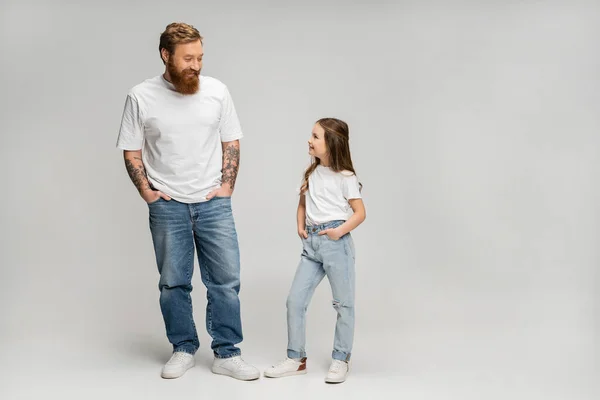 Longitud completa de padre e hija alegres posando sobre fondo gris - foto de stock