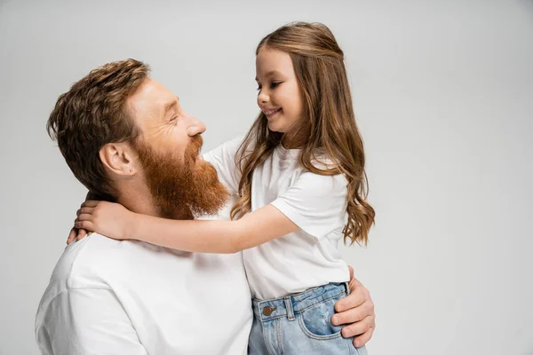 Sonriente niña preadolescente abrazando papá barbudo aislado en gris - foto de stock