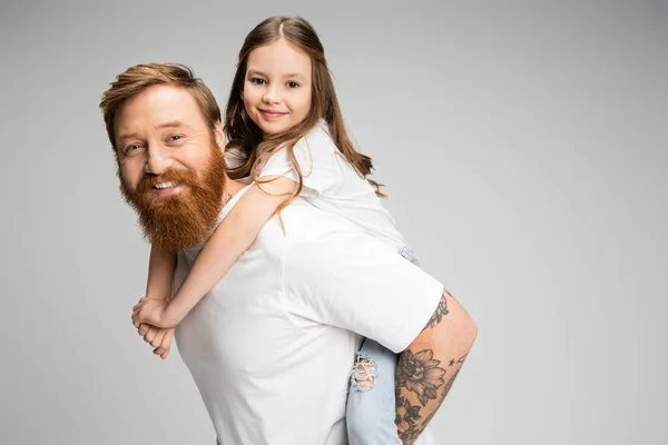 Позитивна дитина свинарство на татуйованому тато ізольовані на сірому — стокове фото