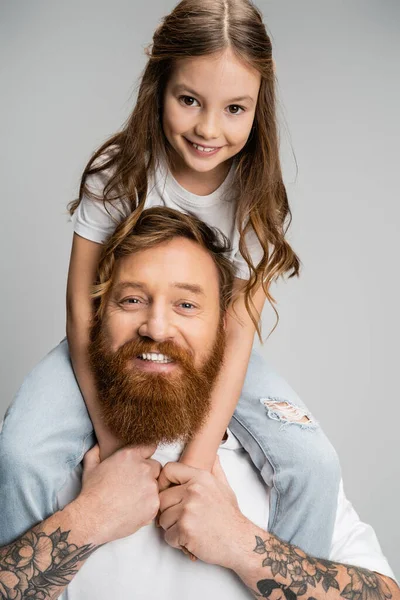 Portrait of girl sitting on shoulders of cheerful dad isolated on grey — Stock Photo