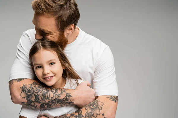 Tattooed father hugging carefree preteen kid isolated on grey — Stock Photo