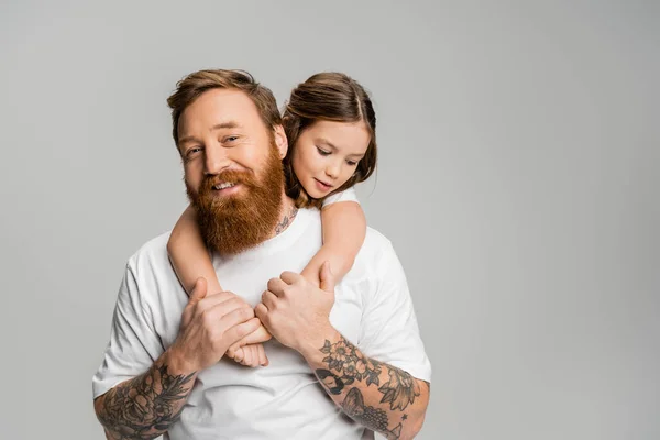 Девочка-подросток, обнимающая татуированного и счастливого отца, изолированного от серых — стоковое фото
