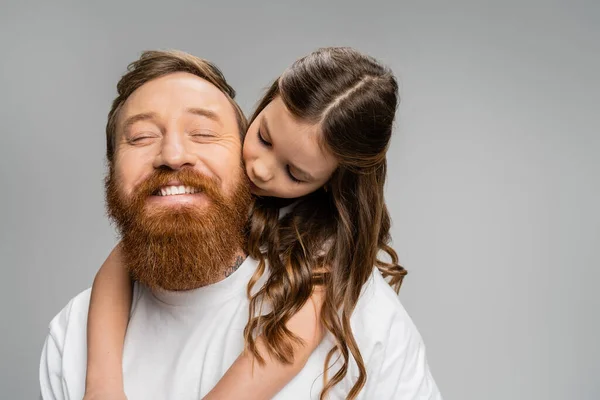 Preteen menina beijando e abraçando sorrindo pai barbudo isolado em cinza — Fotografia de Stock