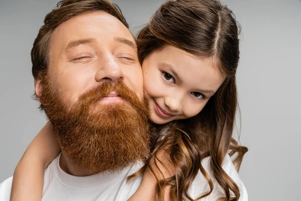 Portrait of positive preteen girl hugging bearded dad isolated on grey — Stock Photo