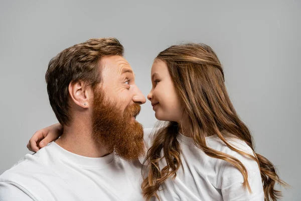 Вид збоку усміхненого батька і дитини, що стоїть носом до носа ізольовано на сірому — стокове фото