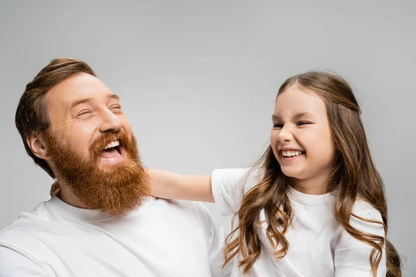 Chico y padre emocionados en camisetas blancas riendo aislados en gris - foto de stock