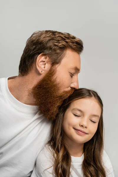 Bearded dad kissing head of smiling preteen daughter with closed eyes isolated on grey — Stock Photo