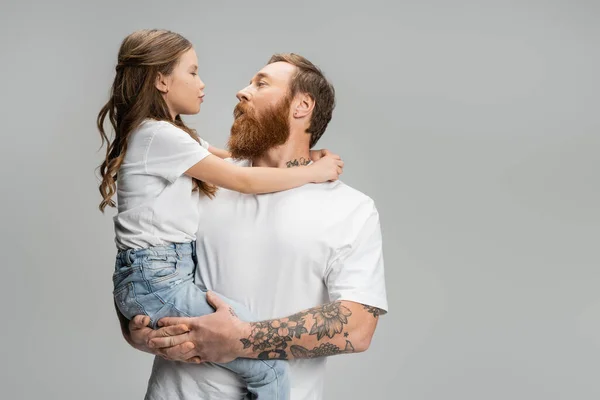 Preadolescente niño haciendo pucheros labios y abrazando barbudo padre aislado en gris - foto de stock