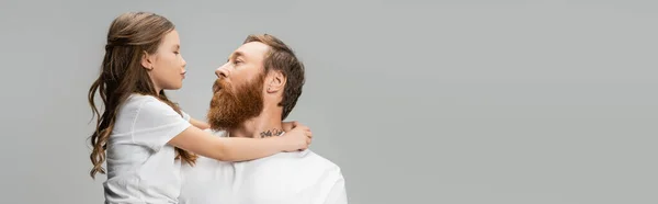 Preadolescente niño haciendo pucheros labios y abrazando papá tatuado aislado en gris, pancarta - foto de stock