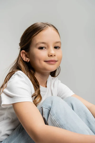 Portrait of smiling preteen girl in jeans and t-shirt looking at camera isolated on grey — Stock Photo