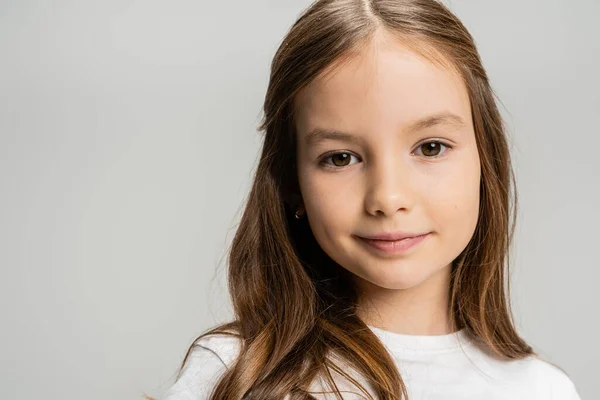 Porträt eines Mädchens im weißen T-Shirt, das isoliert in die Kamera auf grau blickt — Stockfoto