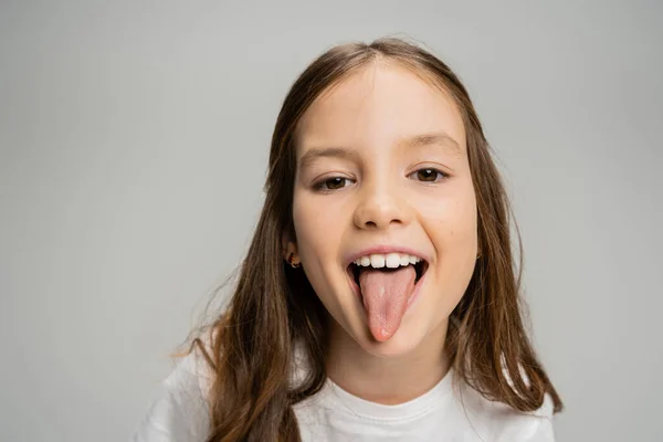 Criança pré-adolescente colando a língua na câmera isolada no cinza — Fotografia de Stock