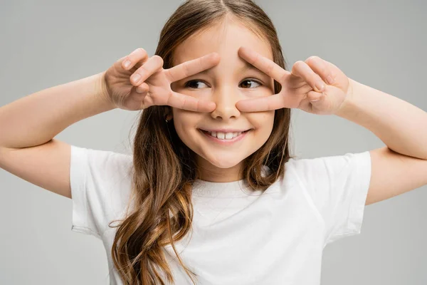 Smiling preteen kid showing peace gesture with hands isolated on grey — Stock Photo