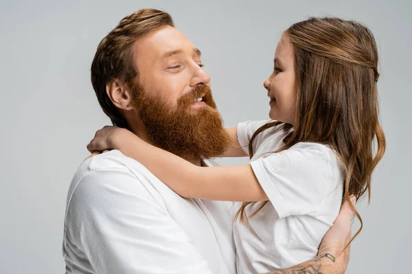 Bearded man hugging cheerful preteen child isolated on grey — Stock Photo