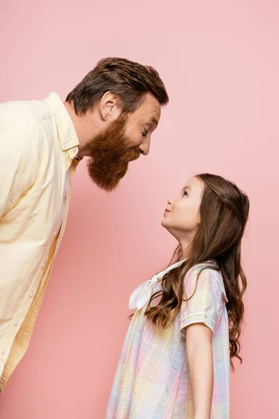 Seitenansicht des fröhlichen Vaters und seiner Tochter, die isoliert auf rosa stehen — Stockfoto