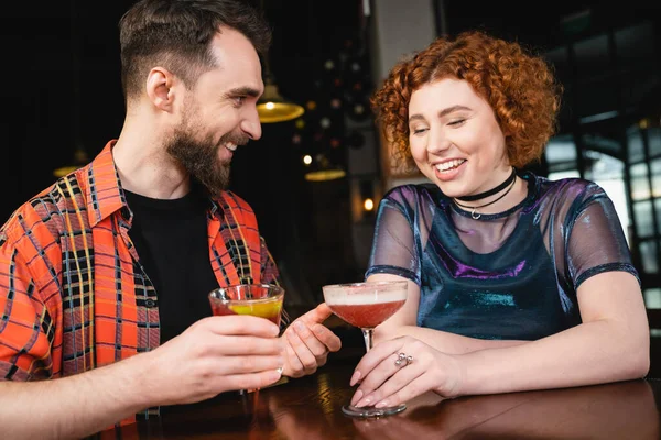 Веселые друзья, держащие коктейли и разговаривающие, проводя время в баре — стоковое фото