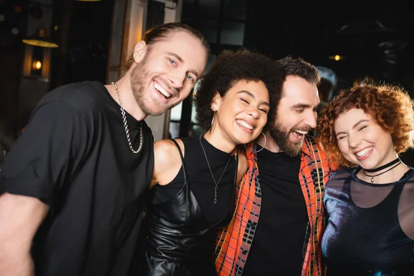 Cheerful interracial people hugging while spending time in bar — Stock Photo