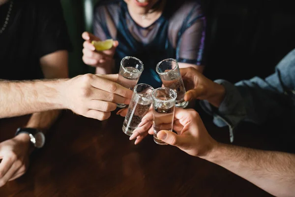 Vista recortada de amigos interracial sosteniendo vasos de tequila con sal en el bar - foto de stock