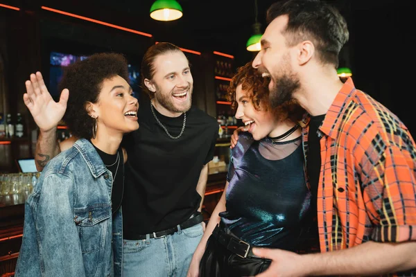 Fröhliche multiethnische Freunde reden, während sie Zeit in einer Bar verbringen — Stockfoto