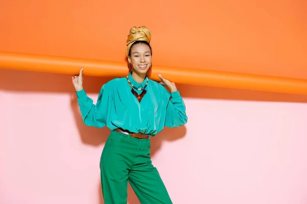 Smiling african american woman in bright outfit posing on colorful background — Stock Photo