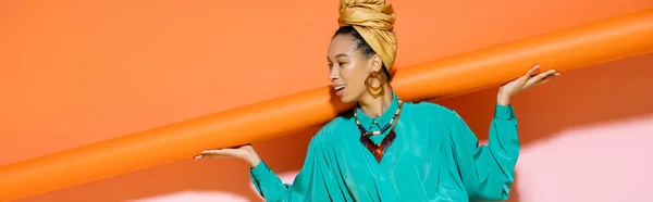 Carefree african fican model with headшарф держащий оранжевый фон, баннер — стоковое фото