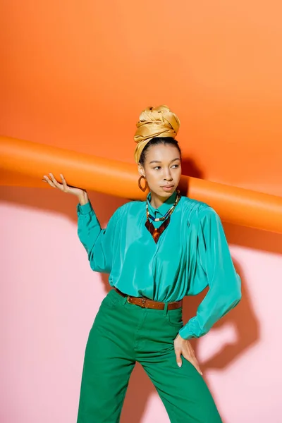 Modelo afroamericano de moda en traje de verano posando con fondo naranja y rosa - foto de stock