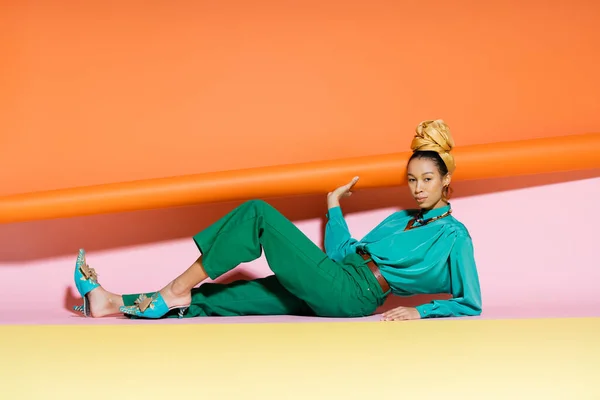 Modelo afroamericano de moda en pañuelo para la cabeza posando sobre un fondo colorido - foto de stock