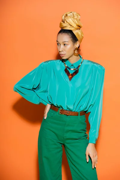 Mujer afroamericana de moda en ropa de verano mirando hacia otro lado sobre fondo naranja - foto de stock